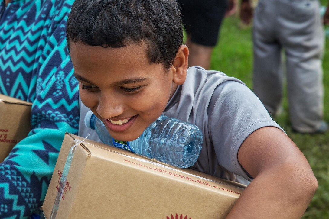 A child smiles after receiving supplies.