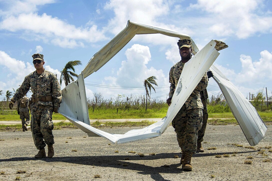 Marines carry big strips of mangled material.