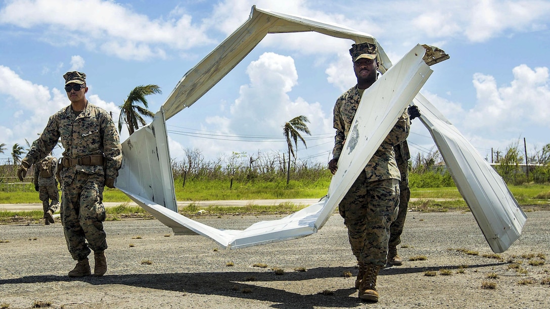 Marines carry big strips of mangled material.