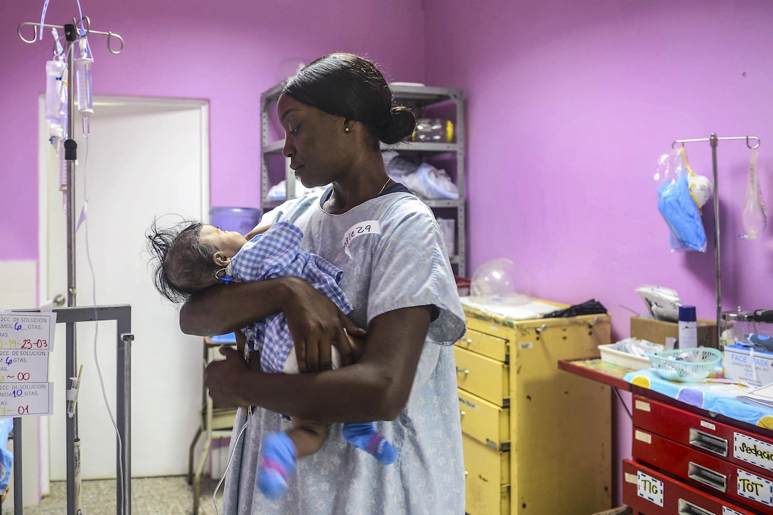 A sailor holds an infant patient in her arms.