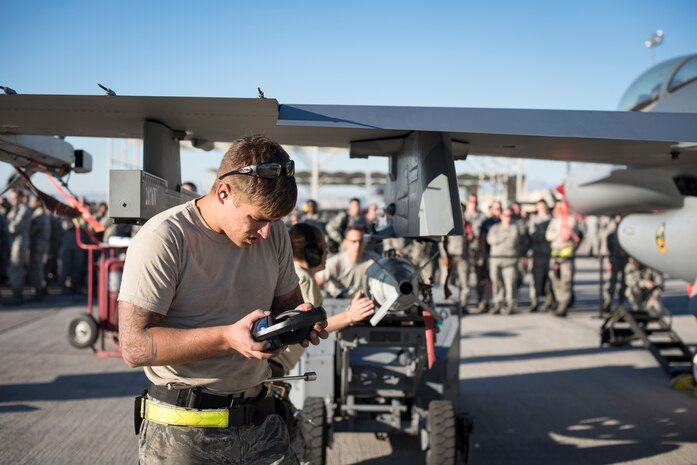 An Airman from the 57th Maintenance Group checks his gear before assembling munitions on an F-16 Fighting Falcon during a load crew competition Oct. 6, 2017, at Nellis Air Force Base, Nev. Each team was tested on their timeliness and accuracy while loading and unloading munitions on their aircraft. (U.S. Air Force photo by Airman 1st Class Andrew D. Sarver/Released)