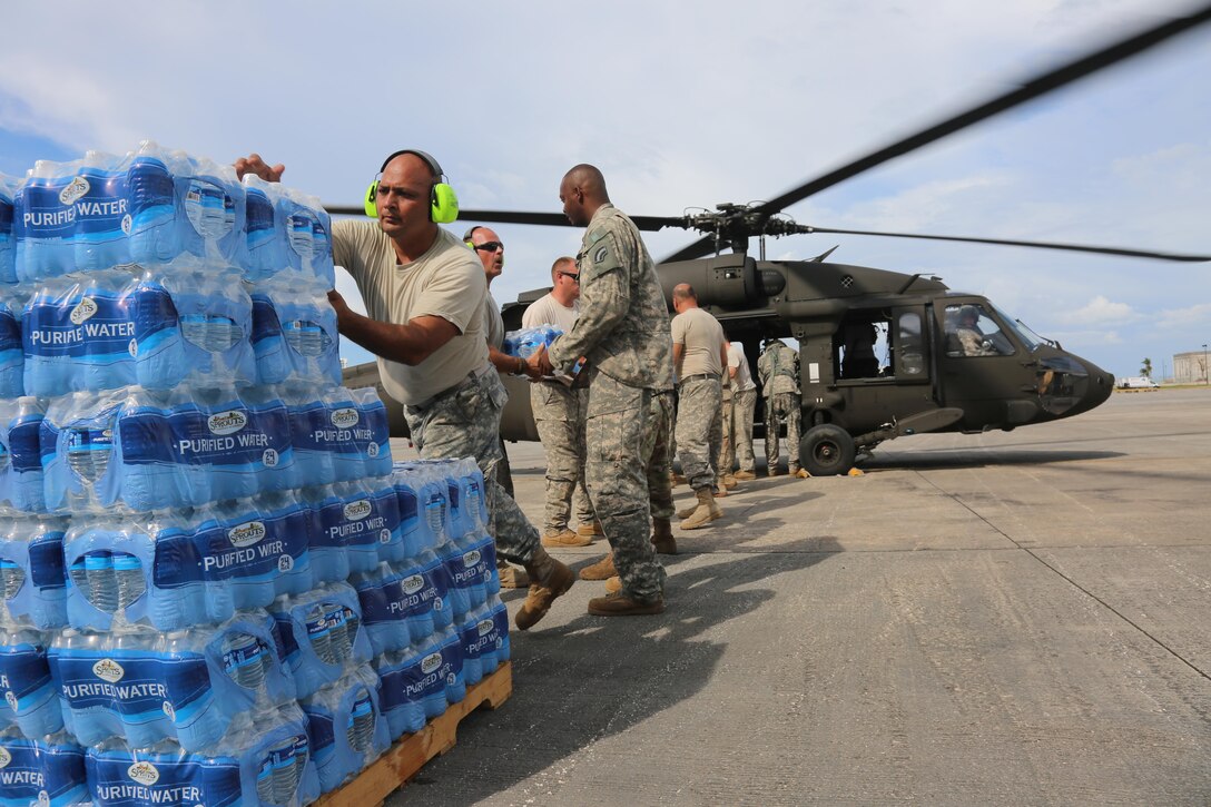 Soldiers load pallets of bottled water onto a helicopter.
