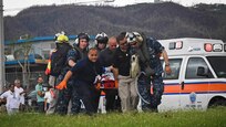 Sailors and other medical personnel move a patient on a stretcher.