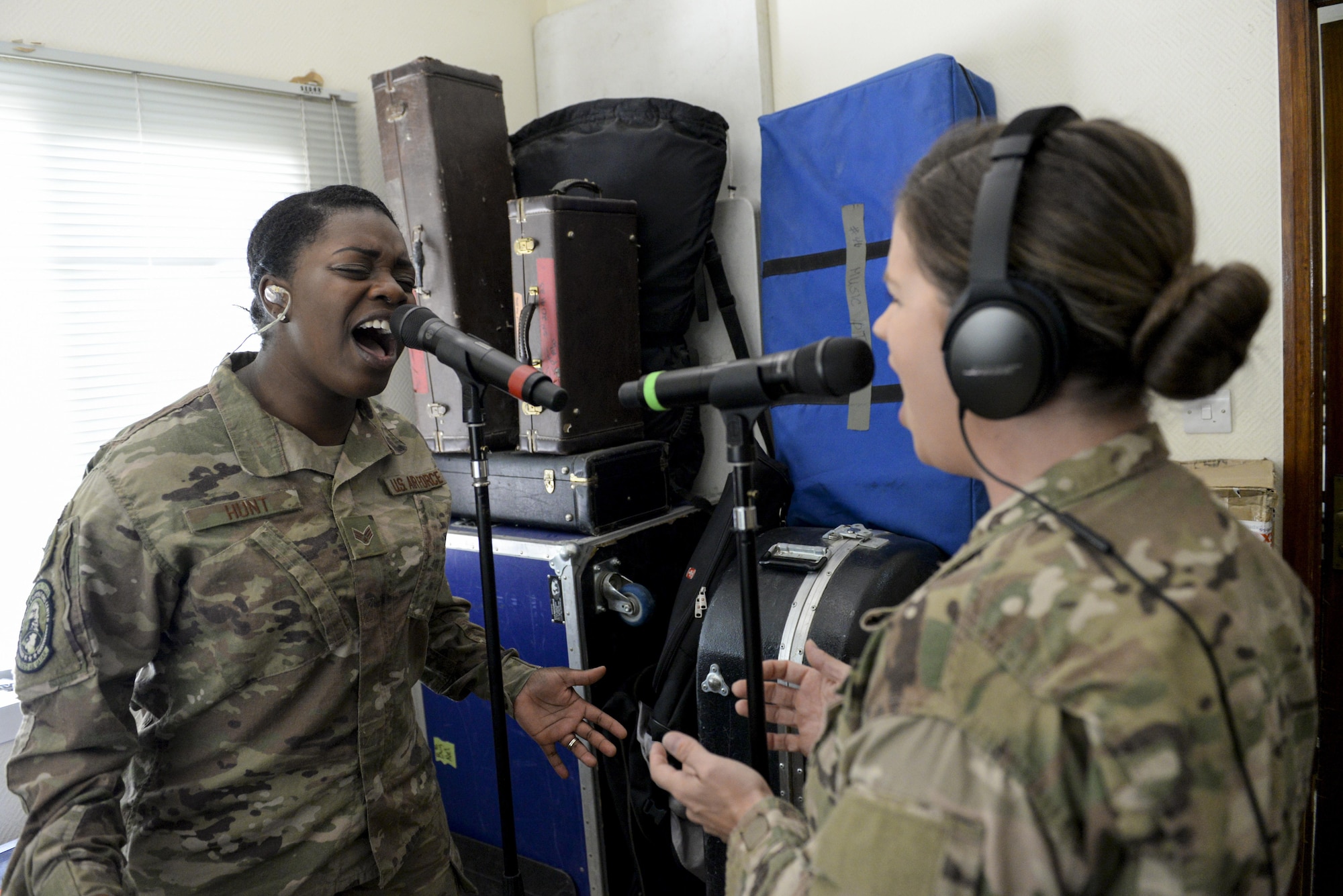 U.S. Air Force Senior Airman Paula Hunt, left, and Staff Sgt. Melissa Lackore, vocalists assigned to the Air Force Central Command Band, Touch-n-Go, sing the Air Force Song during a recording session at Al Udeid, Air Force Base, Qatar, Sept. 21, 2017.