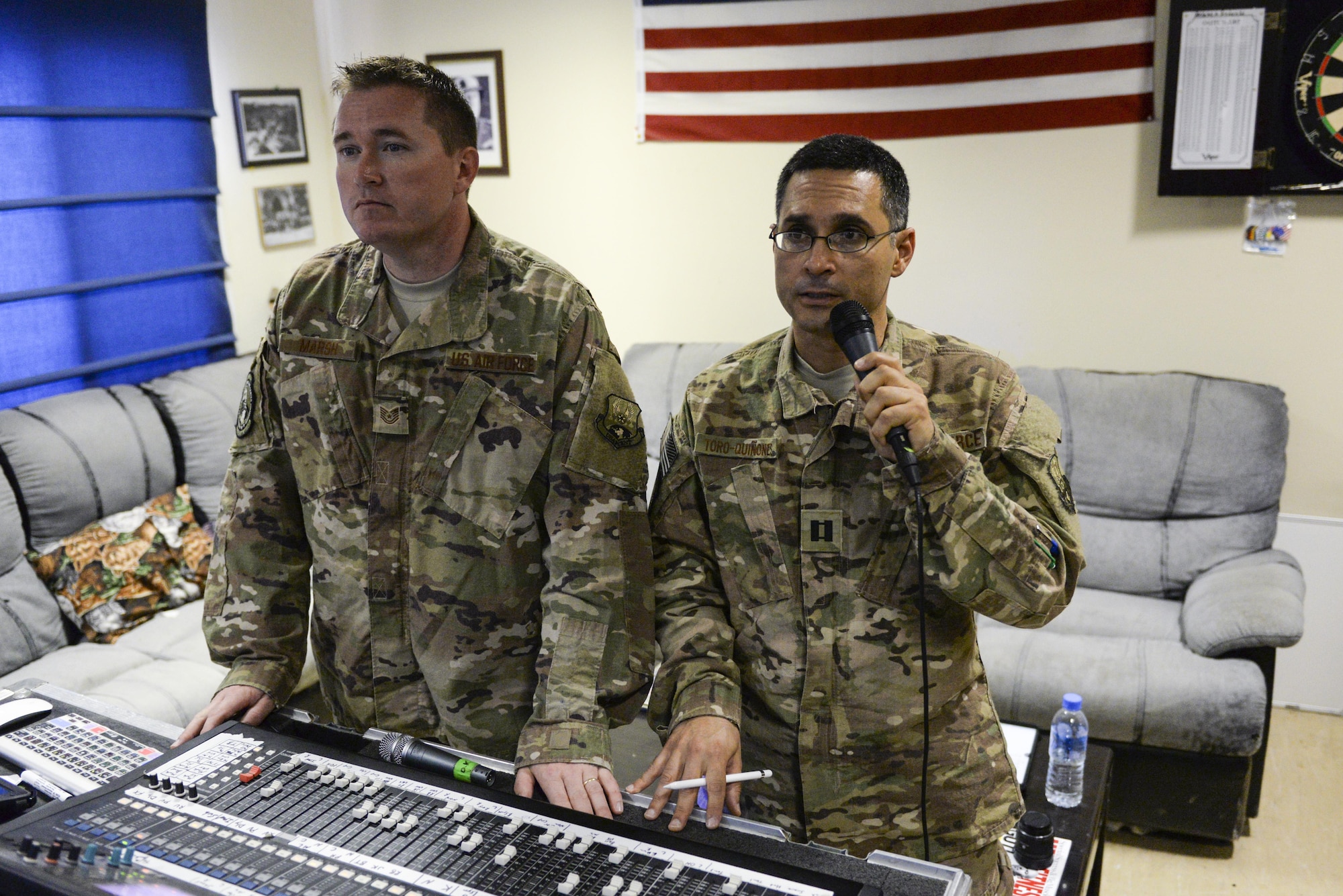 U.S. Air Force Capt. Rafael Toro-Quinones, right, officer in charge, communicates with band members recording in another building while Tech. Sgt. John Marsh, audio engineer, both assigned to the Air Force Central Command Band, Touch-n-Go, assists with the production during a recording session as the band recorded their punk rock rendition of the Air Force Song at Al Udeid, Air Force Base, Qatar, Sept. 21, 2017.