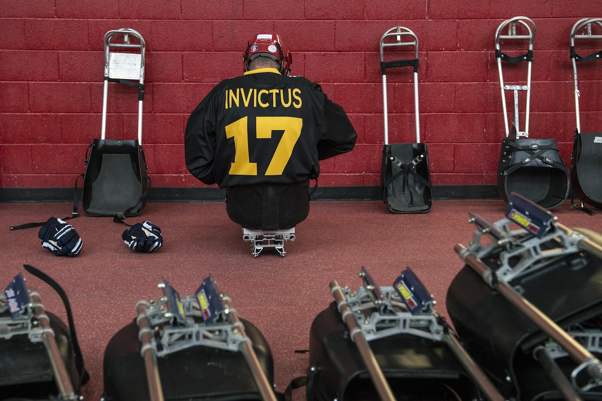 A sledge hockey player faces a red wall as he prepares for a match.