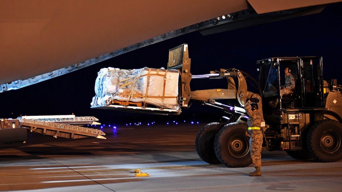 Airmen place a supply pallet onto a C-130 aircraft.
