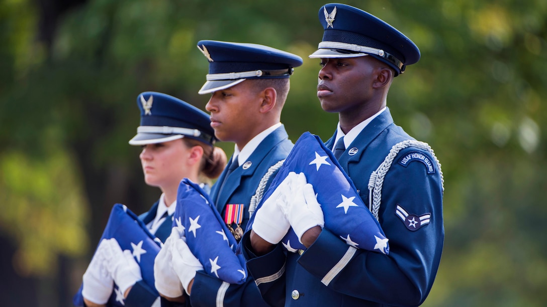 Three members of the Air Force Honor Guard hold the folded U.S. flag.