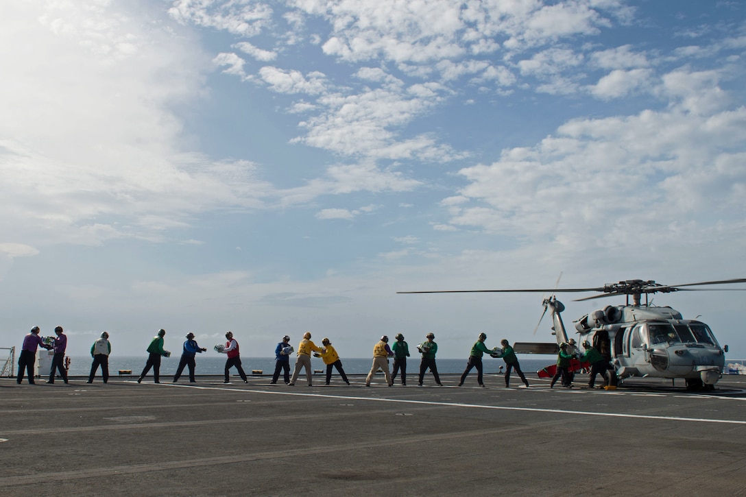 Sailors load water onto an MH-60S Seahawk.