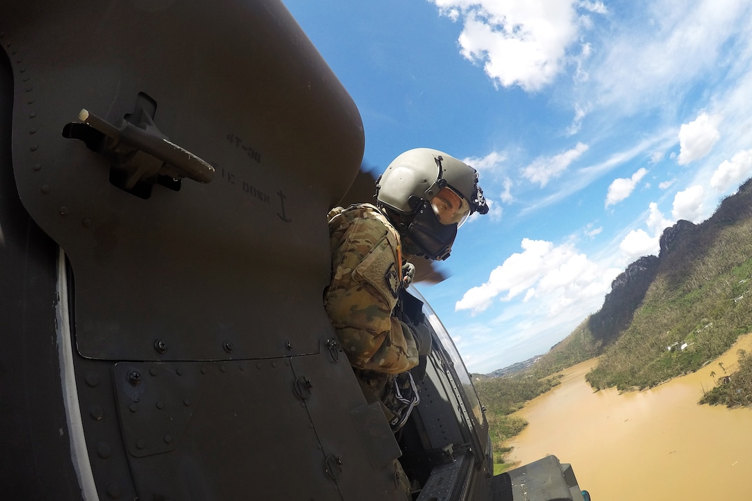 Army Sgt. Michael Villasenor looks out the side window from a UH-60M Black Hawk helicopter for obstructed roadways and isolated villages.