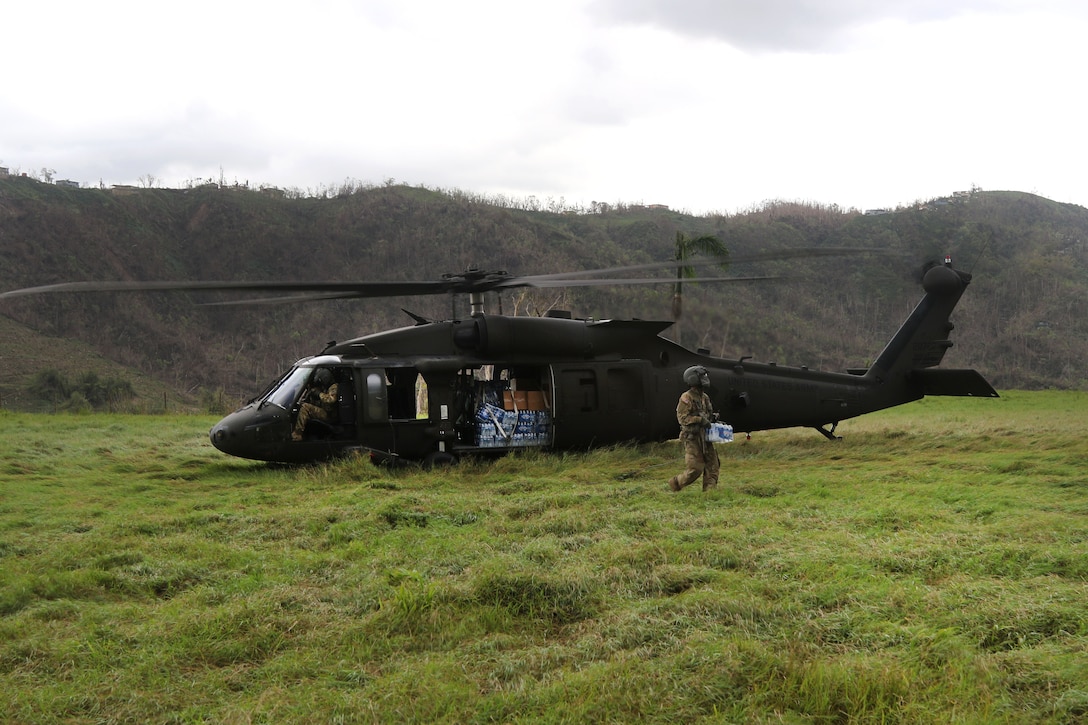 Army Spc. Taylor Suarez delivers water and food from a UH-60M Black Hawk helicopter to an isolated village.