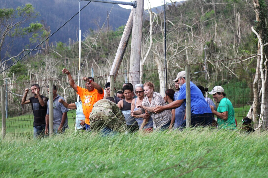 A soldier delivers water from a UH-60M Black Hawk helicopter to the residents of an isolated village.