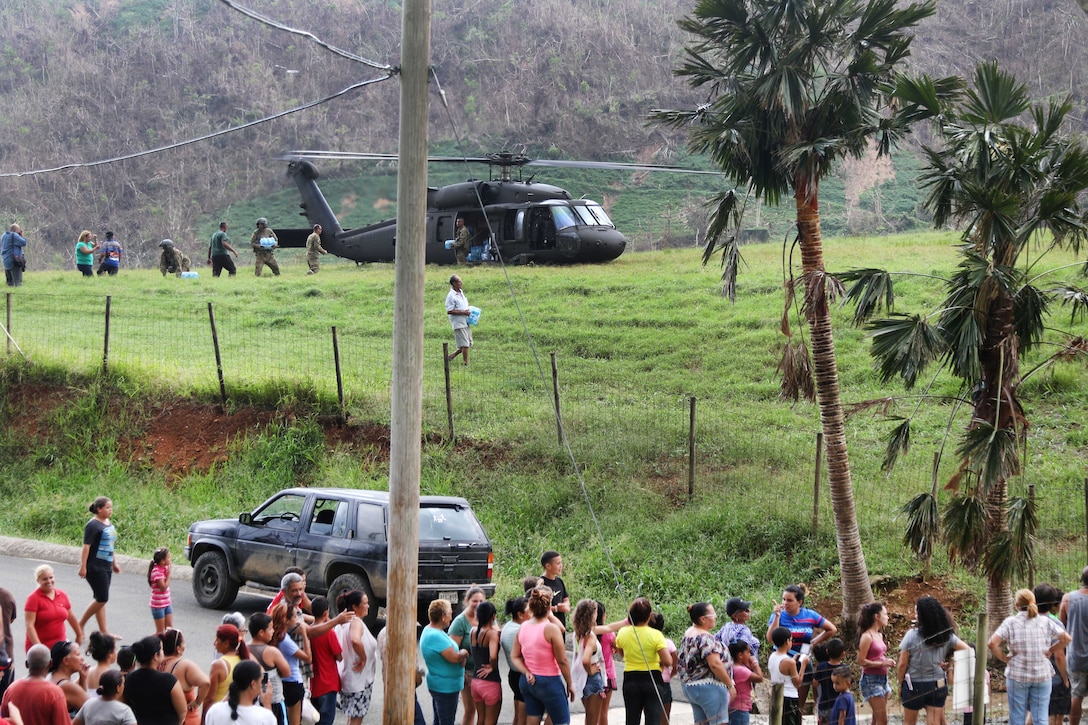 Soldiers deliver water from a UH-60M Black Hawk helicopter to the residents of an isolated village.