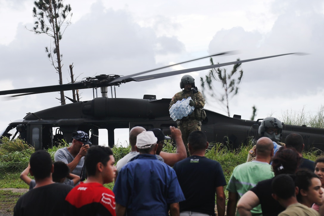 Army Sgt. Michael Villasenor delivers water from a UH-60M Black Hawk helicopter to the residents of an isolated village.