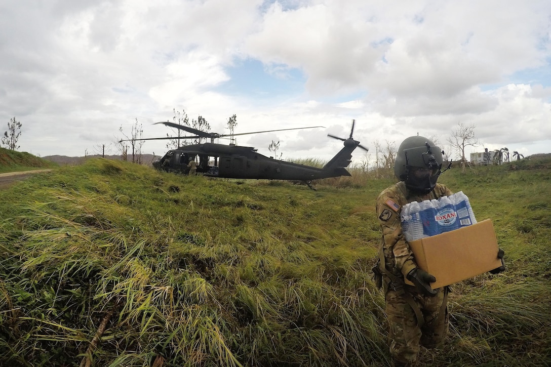 Army Sgt. Michael Villasenor delivers water and food from a UH-60M Black Hawk helicopter to the residents of an isolated village.