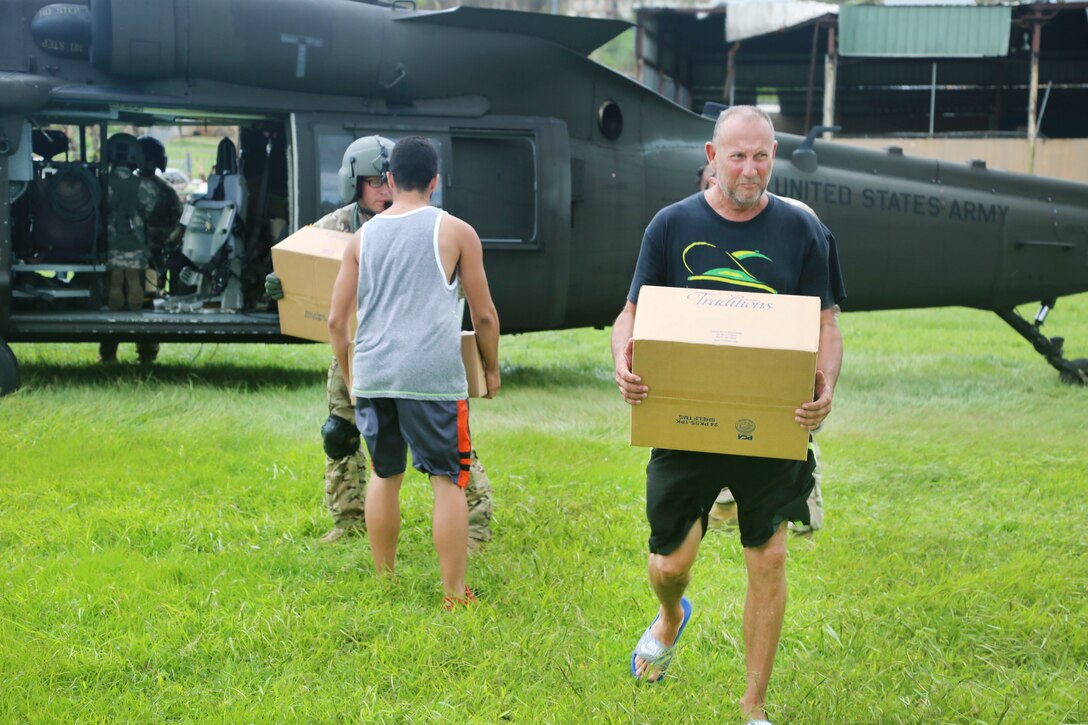 Soldiers unload food and water from a HH-60 Black Hawk helicopter for local residents near San Juan.