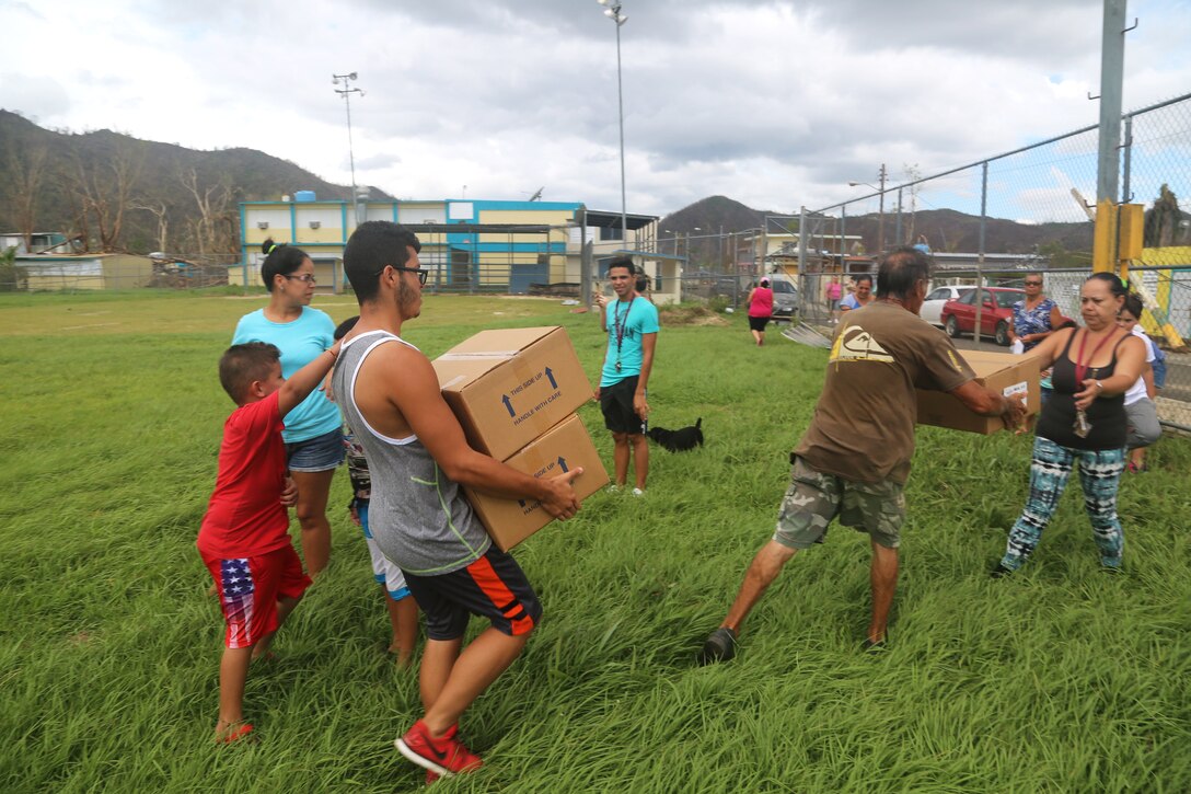Puerto Ricans receive food and water from soldiers after offloading from a HH-60 Black Hawk helicopter near San Juan.