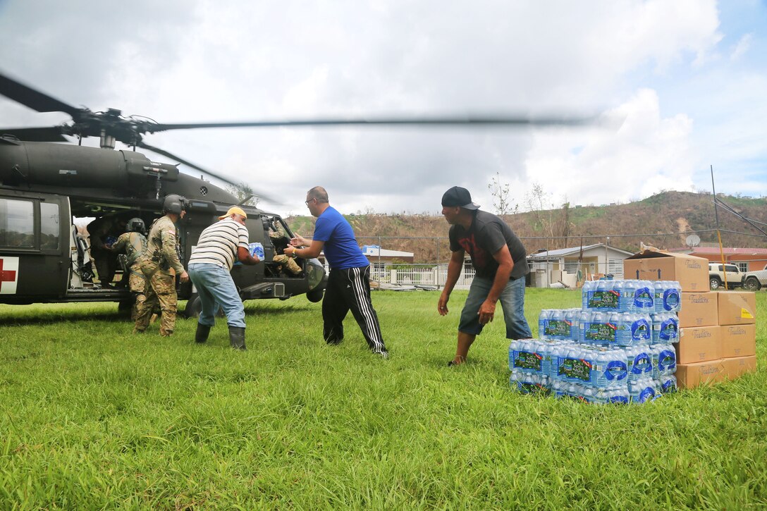 Soldiers work with the local residents to unload food and water from a HH-60 Black Hawk helicopter near San Juan.