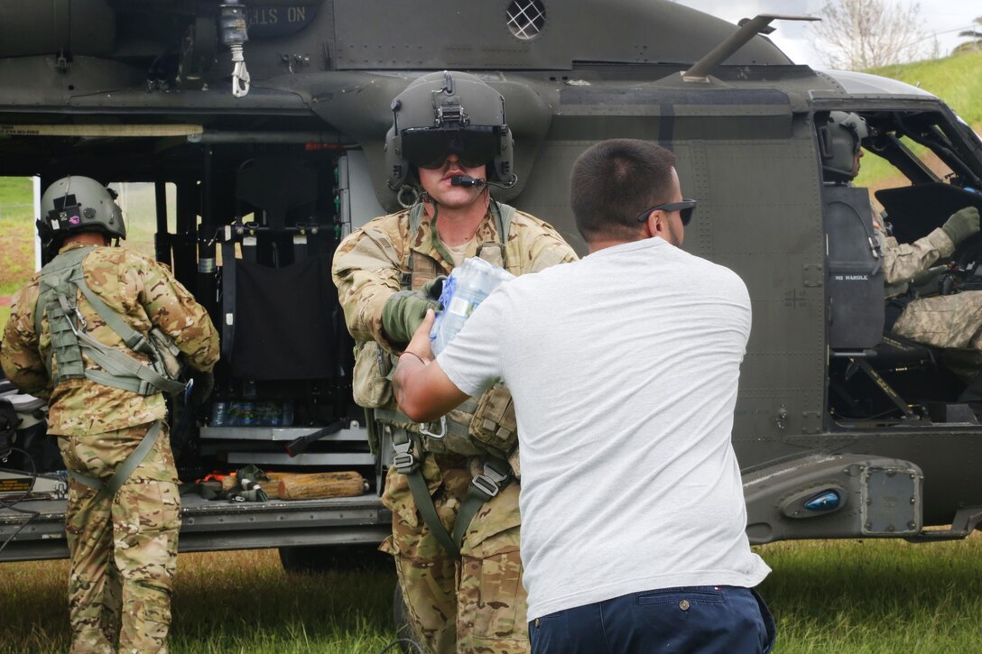 Soldiers work with the local residents to unload food and water from a HH-60 Black Hawk helicopter near San Juan.