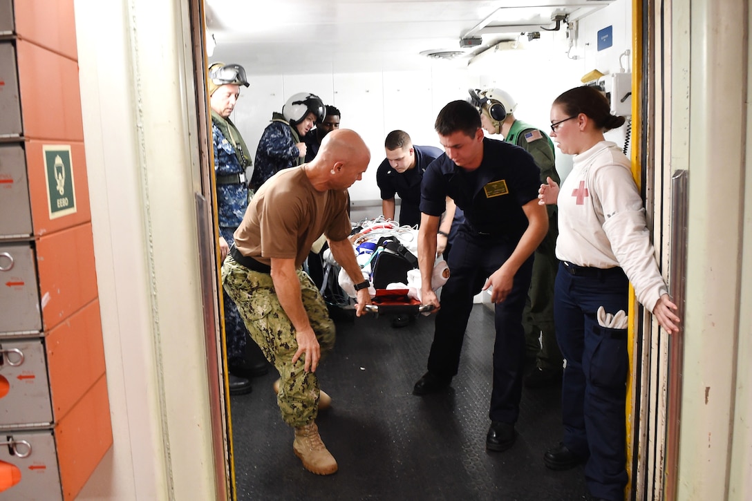 Sailors move a patient on a stretcher to a medical treatment room after arriving from Menonita Hospital in Caguas, Puerto Rico, on board the hospital ship USNS Comfort.