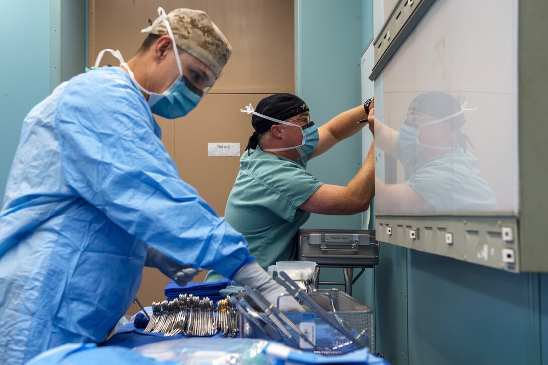 Navy Petty Officer 2nd Class Felix Perez, left, and Lt. Samuel McJuckin prepare for a surgical operation.