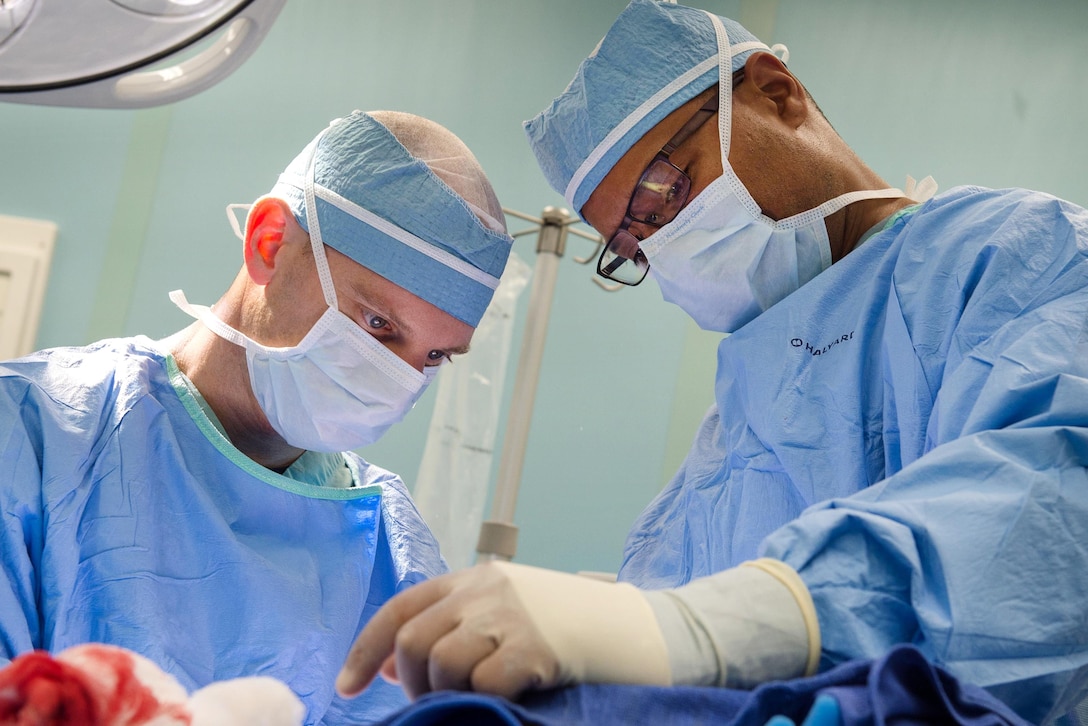 Navy Cmdrs. Matt Bradley, left, and Elliot Jessie perform a surgical operation in an operating room aboard the hospital ship USNS Comfort.