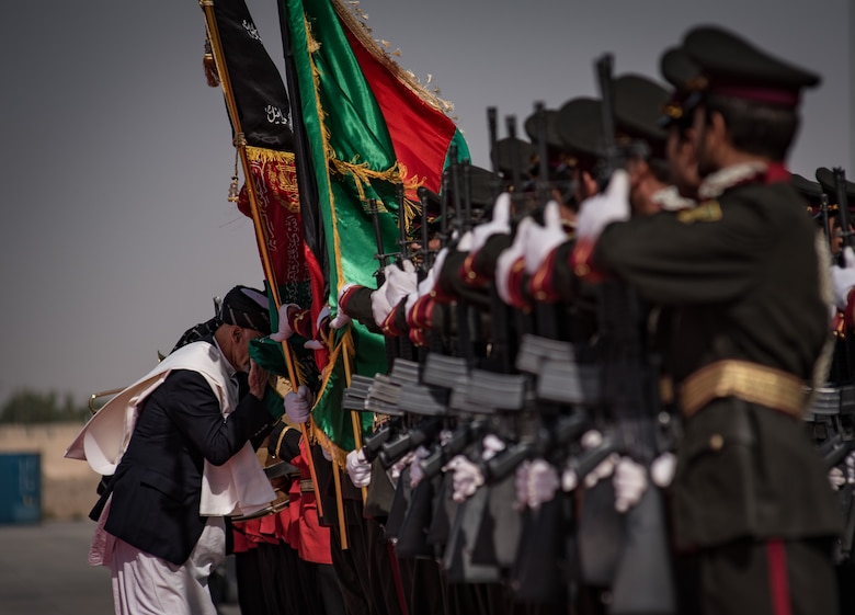 Afghanistan President Ashraf Ghani, left, ceremonially touches the Afghan national flag to his face Oct. 7, 2017, at Kandahar Airfield, Afghanistan. Ghani attended an inaugural ribbon cutting, commemorating the arrival of the UH-60 helicopter to the Afghan Air Force fleet. (U.S. Air Force photo by Staff Sgt. Alexander W. Riedel)