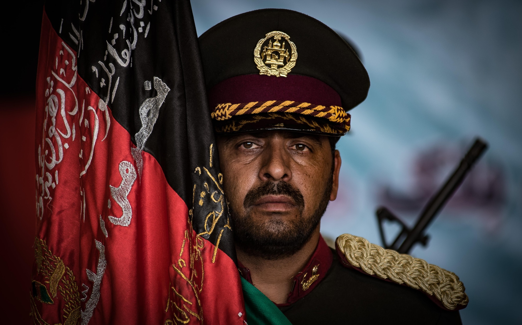 An Afghan National Security and Defense Forces honor guardsman stands beside a ceremonial flag during the UH-60 Black Hawk transfer ceremony Oct. 7, 2017, at Kandahar Airfield, Afghanistan. Officials signed a transfer of ownership certificate and performed a ceremonial ribbon cutting celebrating the newest addition to Afghanistan’s growing air force fleet. (U.S. Air Force photo by Staff Sgt. Alexander W. Riedel)