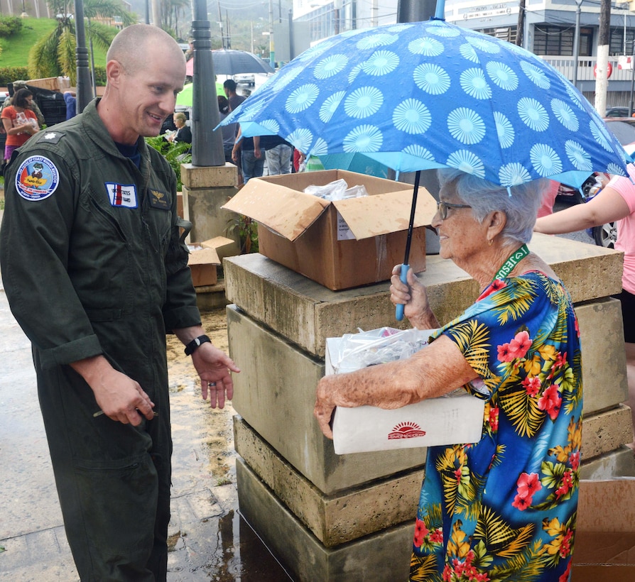 Coast Guard Cmdr. Jeremy Anderson delivers a box of food and water to a resident of Moca.