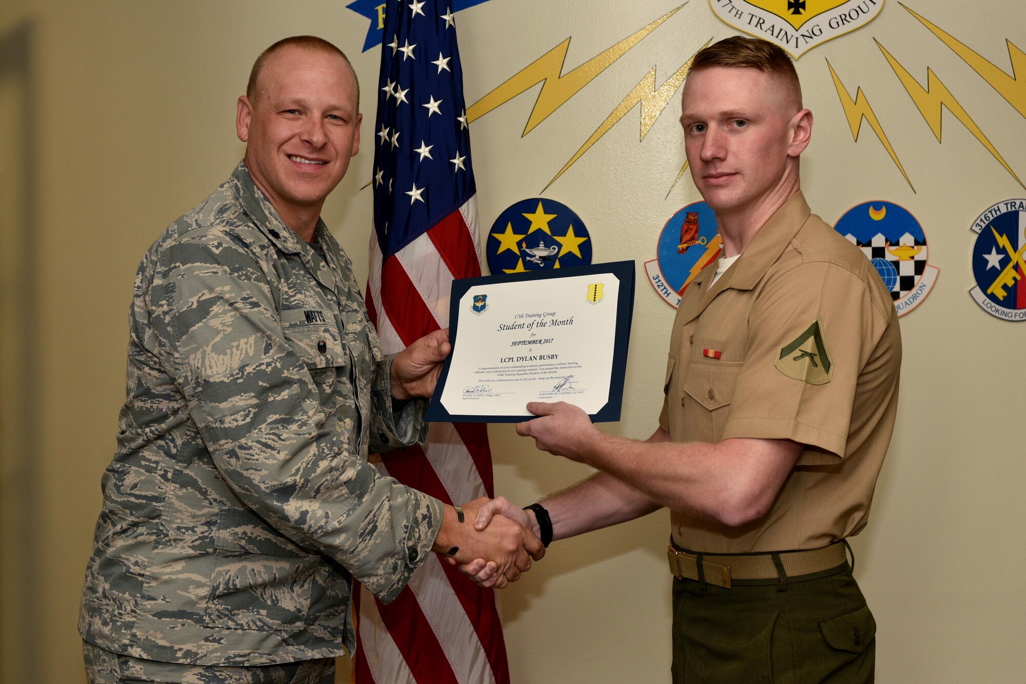 U.S. Air Force Lt. Col. Steven Watts, 17th Training Group deputy commander, 315th Training Squadron Student of the Month award for Sept. 2017 to U.S. Marine Corps Lance Cpl. Dylan Busby, 316th Training Squadron trainee, in the Brandenburg Hall on Goodfellow Air Force Base, Texas, Oct. 5, 2017. The 17th Training Wing's mission is to develop and inspire exceptional intelligence, surveillance and reconnaissance, and fire protection professionals for America and her allies. (U.S. Air Force photo by Airman 1st Class Randall Moose/released)