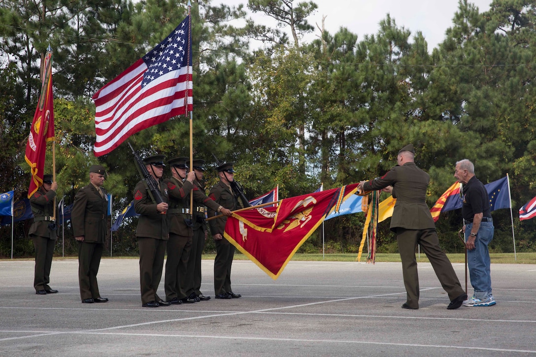 A retired Marine who served with 8th Marine Regiment is escorted to place a banner on the 8th Marine Regiment flag during the unit’s 100th anniversary ceremony at Camp Lejeune, N.C., Oct. 6, 2017. Marines of past and present gathered to commemorate the 100th anniversary of the inception of 8th Marine Regiment. The unit was established Oct. 9, 1917. (U.S. Marine Corps photo by Pfc. Nicholas Guevara)