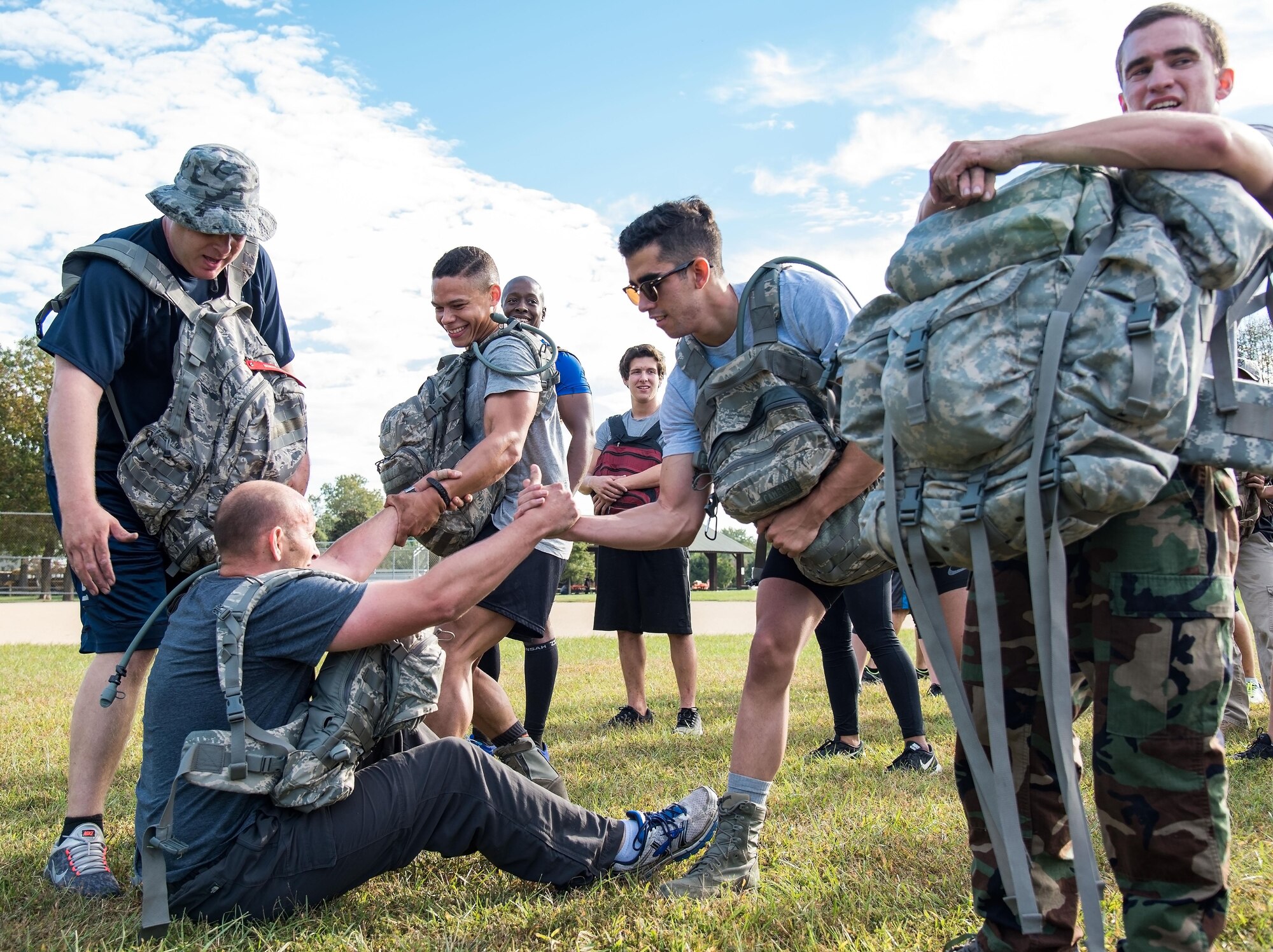GORUCK participants help a member up after completing a warm-up exercise Oct. 6, 2017, at Brecknock Park in Camden, Del. Thirty-one individuals participated in the 2017 GORUCK Light Challenge that teaches participants how to overcome adversity by working as a team. (U.S. Air Force photo by Roland Balik)