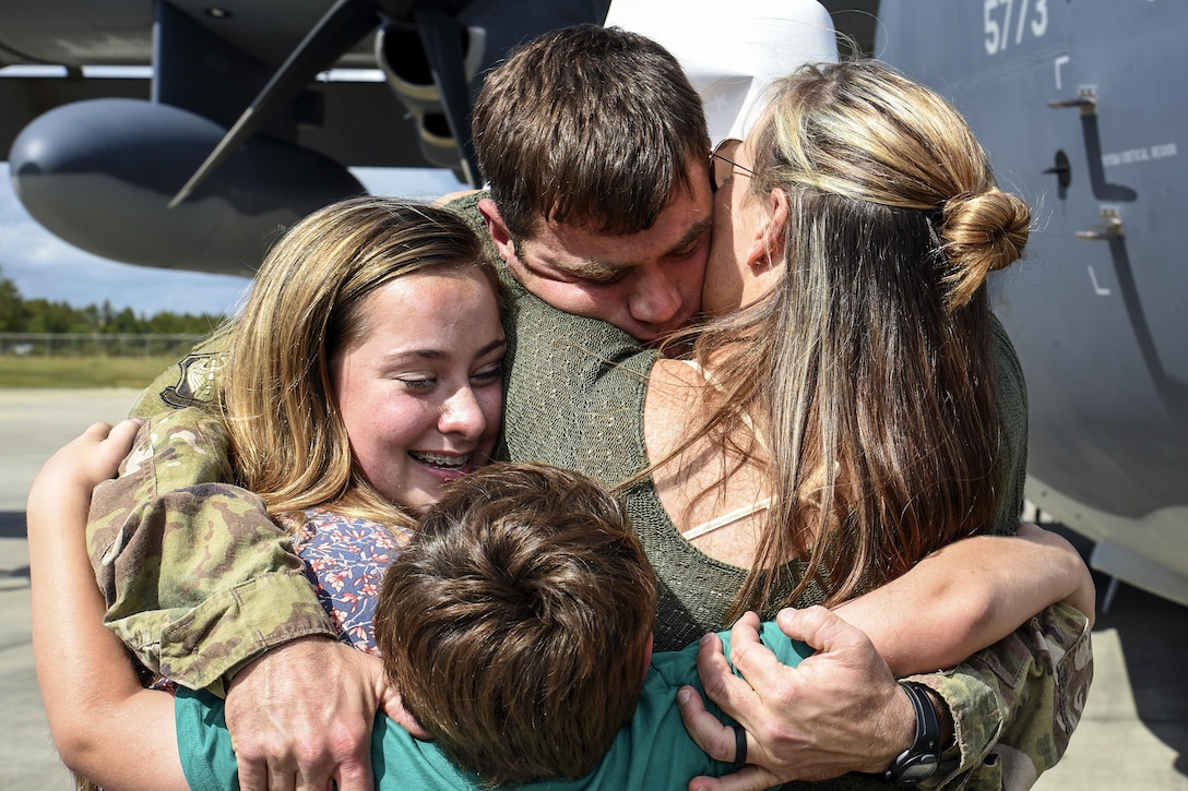 An airman hugs several members of his family.