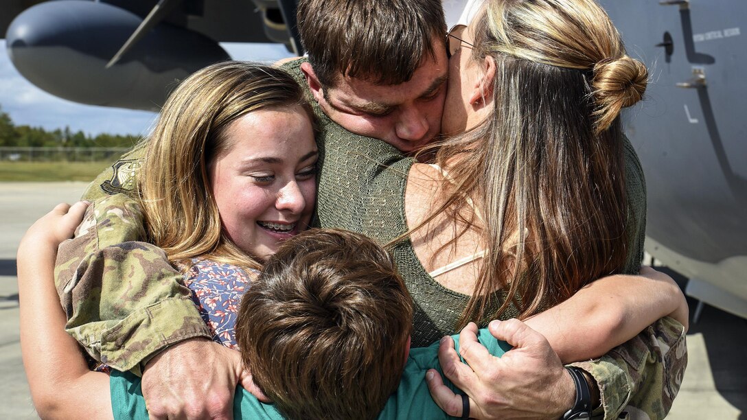 An airman hugs several members of his family.