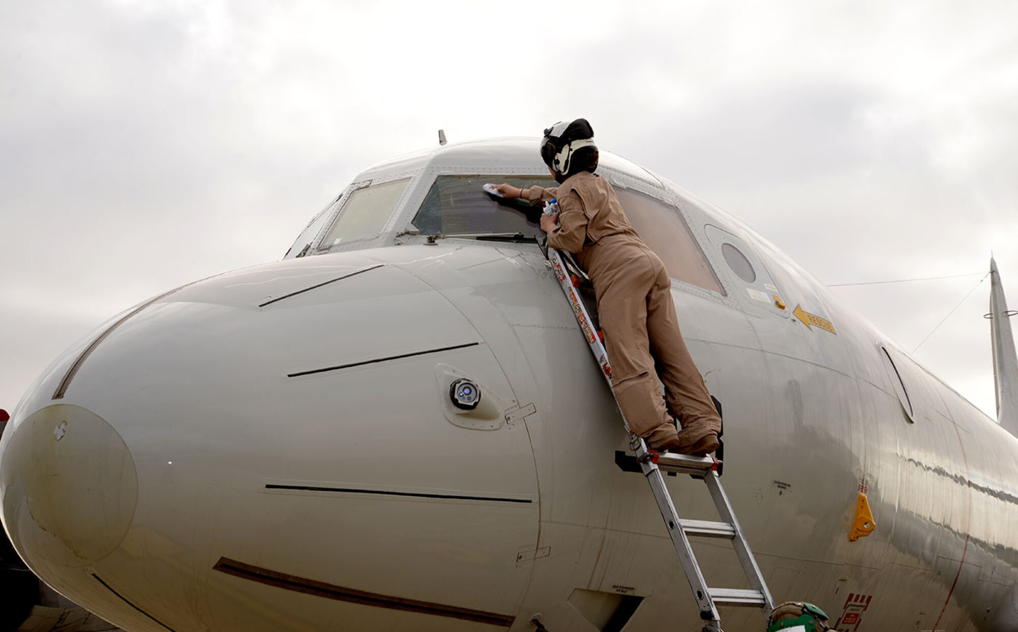 A U.S. Navy crewmember from the VP-46 Grey Knights cleans the window of a P-3C Orion aircraft as the jet prepared to leave Oct. 2, 2017, on RAF Mildenhall, England. Two U.S. Navy aircraft were returning from a six-month deployment in support of U.S. Central Command operations and stopped overnight at RAF Mildenhall on their way home to Naval Air Station Whidbey Island, Wash. (U.S. Air Force photo by Karen Abeyasekere)