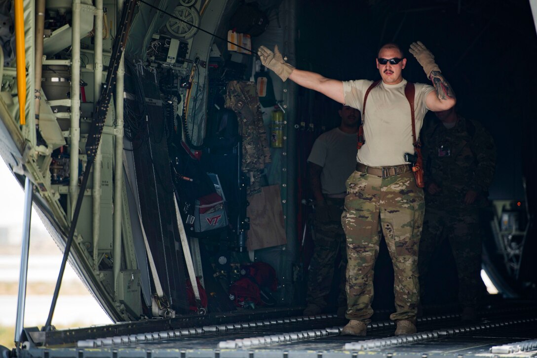 Airman 1st Class Alex Douglas uses hand signals to direct the placement of cargo onto a C-130J Super Hercules aircraft.