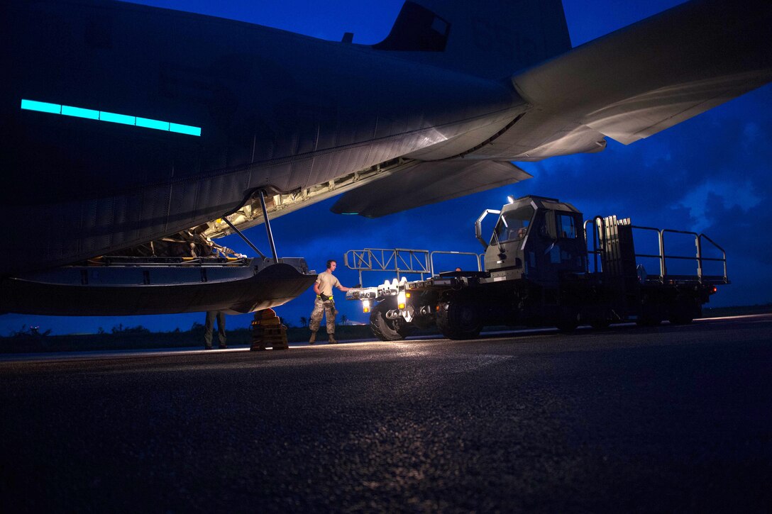 Senior Airmen Wesley LaPrarie guides a Halvorsen K-loder toward the back of a KC-130 Super Hercules aircraft during night operations.