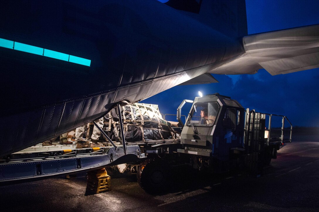 Airmen offload supplies from a Marine Corps KC-130 Super Hercules aircraft during night operations.