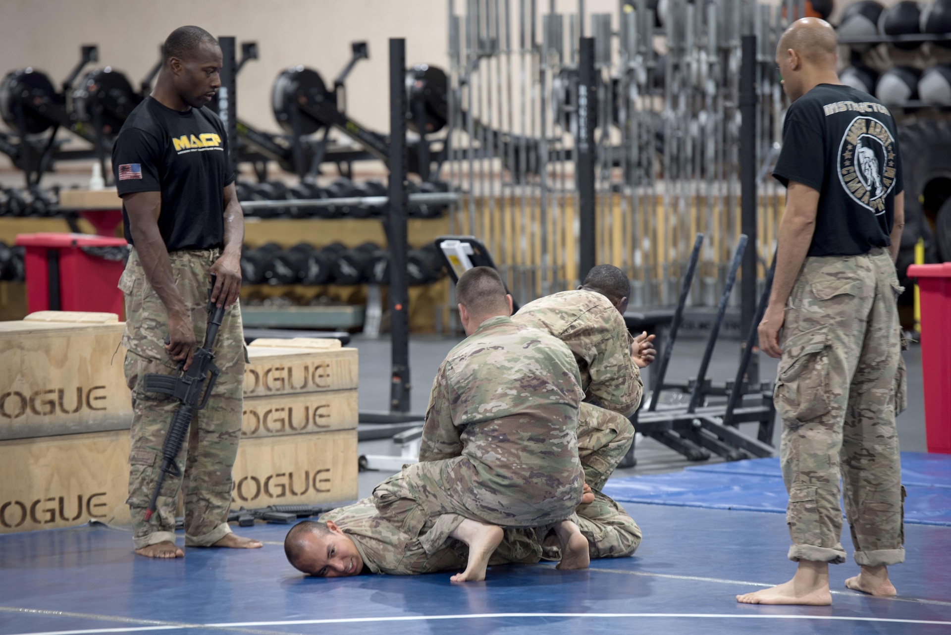 Instructors provide guidance to a group of Soldiers practicing hand-to-hand combat.