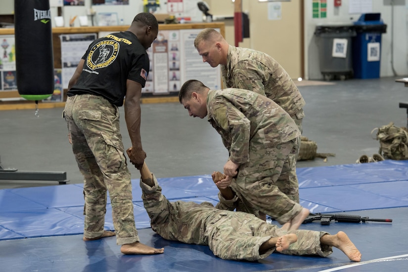 Instructor provides guidance to a group of Soldiers practicing hand-to-hand combat.