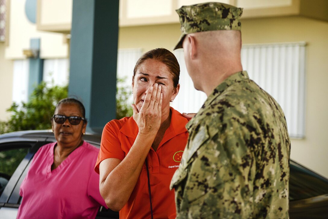 A woman cries as while talking with a service member.