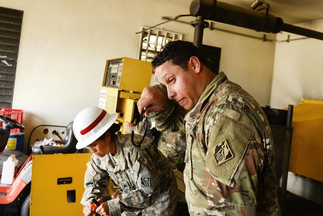 Army Spc. Richard Alicea, right, and Sgt. Natchaya Chotamungsa install a generator.