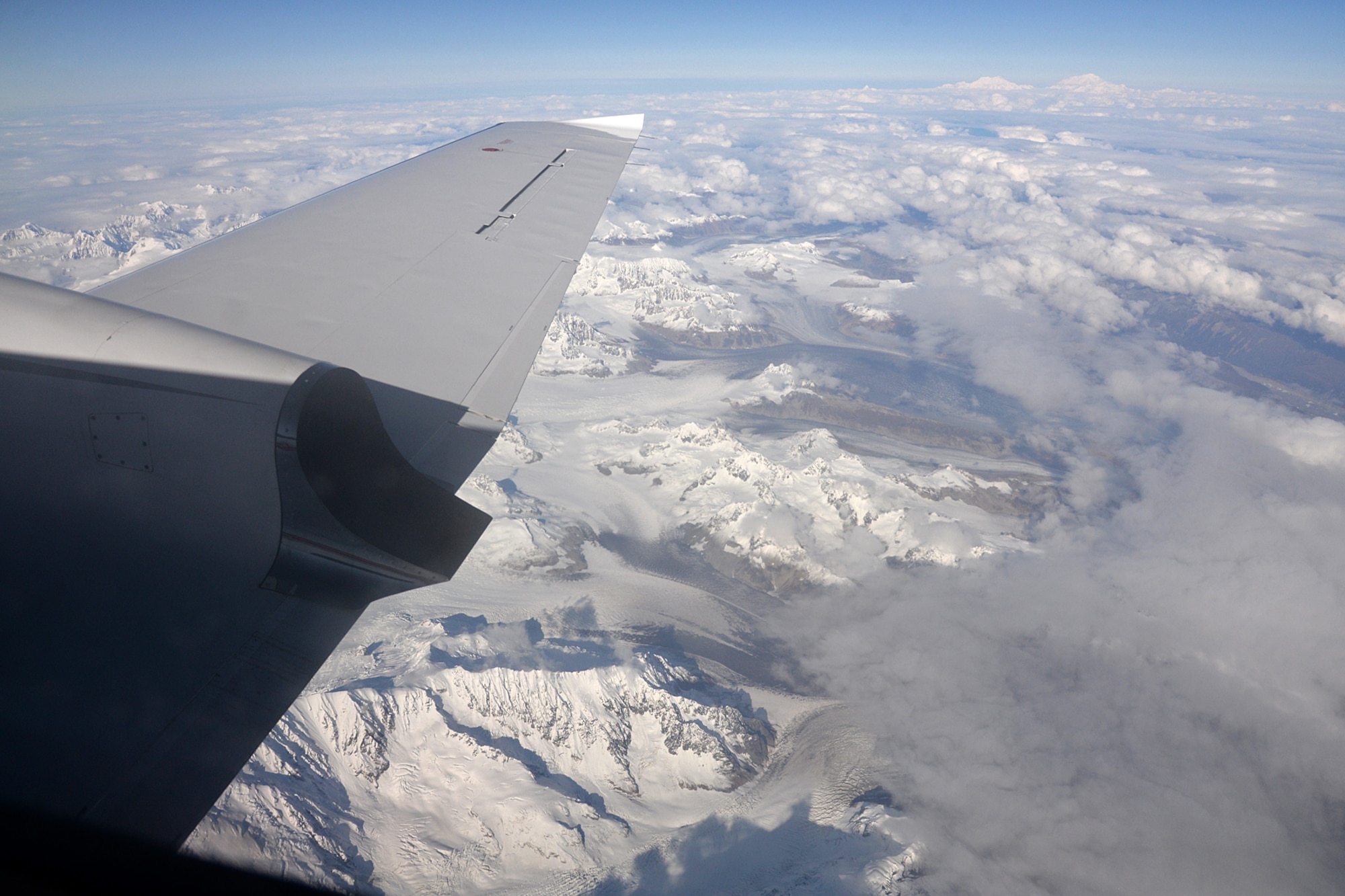 A chartered Cessna Conquest II aircraft flies over the Tordrillo Mountain Range on Sep. 25, 2017, on its way to Cape Romanzof, Alaska. Below the aircraft is Triumvirate Glacier and in the distance (top right) are the mountains Foraker and North America’s highest mountain, Denali. (U.S. Air Force photo by Alex R. Lloyd)