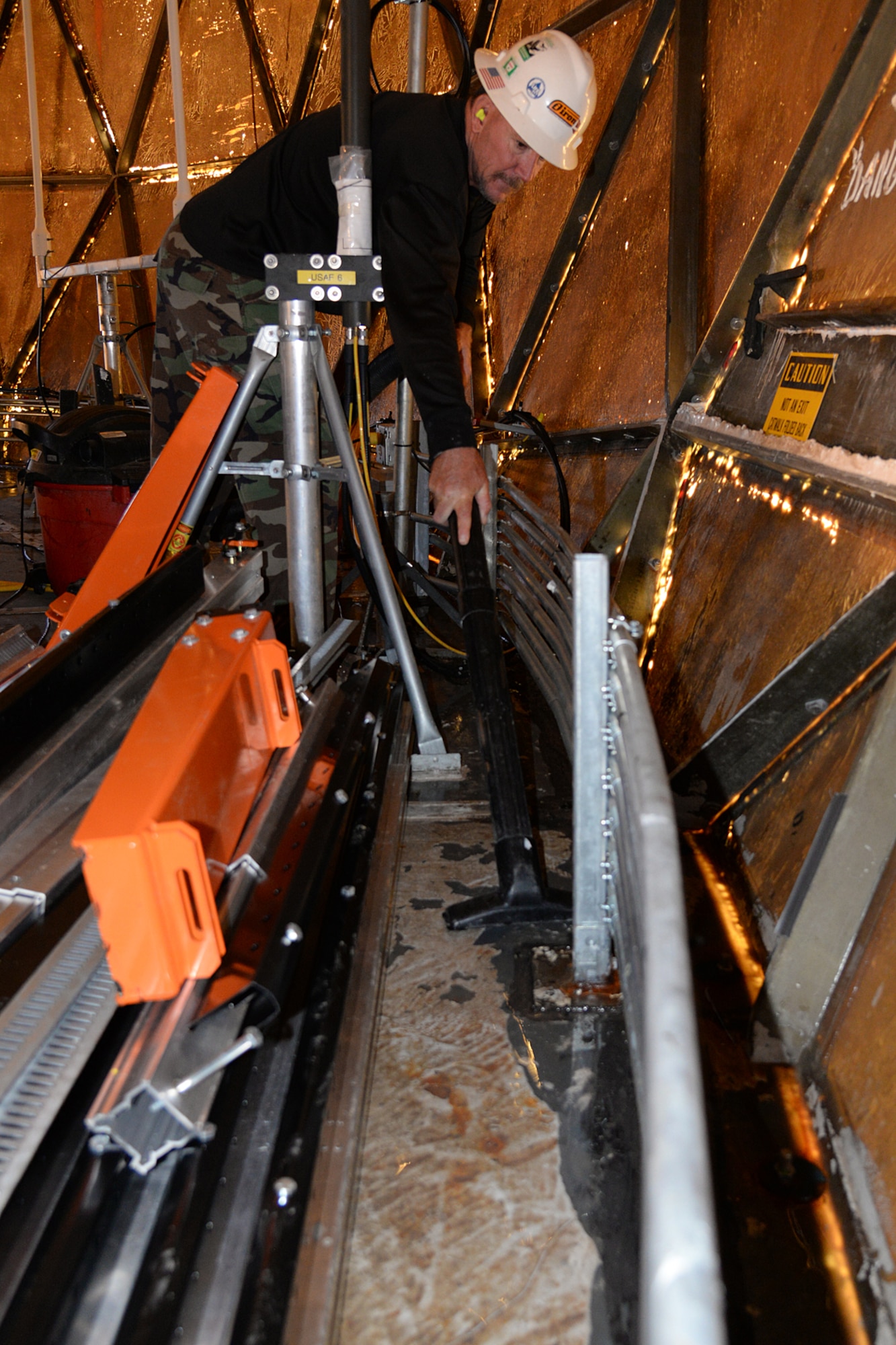 Jim Egbert vacuums up water thatcollected around the base ring bolts at Cape Romanzof, Alaska, on Sep. 26, 2017. Base ring bolt are checked during each maintenance visit. (U.S. Air Force photo by Alex R. Lloyd)