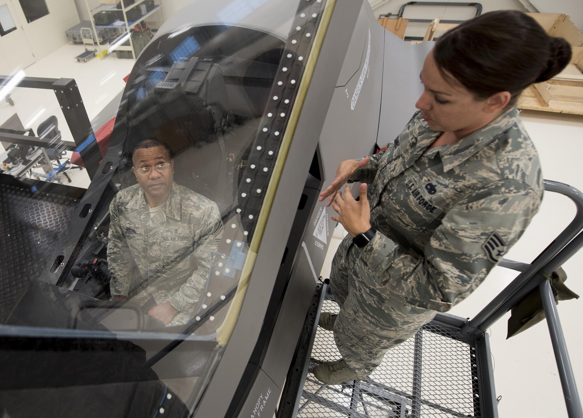 U.S. Air Force Staff Sgt. Amanda Dennis, F-35 Field Training Detachment egress instructor, explains an F-35 ejection seat maintenance trainer to Chief Master Sgt. David Brown, 19th AF command chief, Oct. 3, 2017, at Eglin Air Force Base, Fla. During Brown's visit at the 33rd Fighter Wing, Brown experienced the one-of-a-kind training facility where F-35 maintainers hone their craft by using state of the art equipment. (U.S. Air Force photo by Staff Sgt. Peter Thompson)