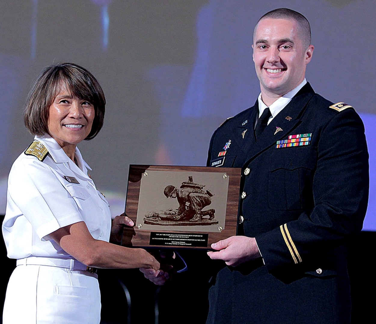 Vice Adm. Raquel Bono, Director, Defense Health Agency, presents Maj. (Dr.) Steven Schauer, of the U.S. Army Institute of Surgical Research at Joint Base San Antonio-Fort Sam Houston. with the 2017 Military Health System Research Symposium award for Outstanding Research Accomplishment (military/individual) Aug. 26.