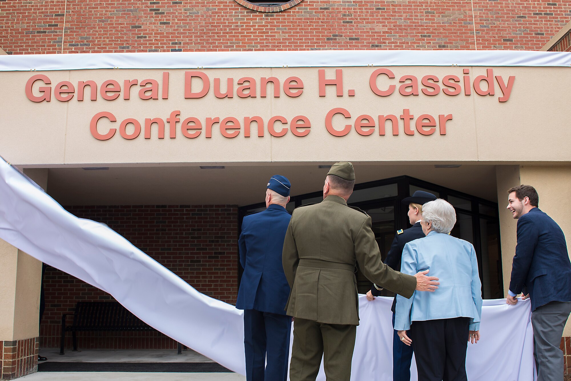 Gen. Carlton D. Everhart II, Air Mobility Command commander, and Marine Lt. Gen. John J. Broadmeadow, U.S. Transportation Command deputy commander, assist members of the Cassidy family unveil the conference center’s new moniker.