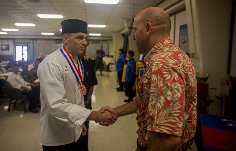Sgt. Scott Maynard, a food service specialist with Headquarters Battalion, Marine Corps Base Hawaii (MCBH), receives his 3rd place medal from Douglas Wadsworth, the base chief of staff, during the “Chef of the Year” competition at Anderson Hall, MCBH, Oct. 4, 2017. The competition pitted each winner or runner-up of the “Chef of the Quarter” cook-off against each other in a series of evaluations including a written test, display/presentation, and creativity. (U.S. Marine Corps photo by Sgt. Ricky Gomez)
