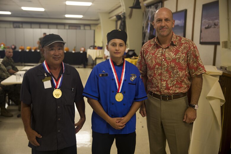 Lance Cpl. Cynthia JaretziCruz, a food service specialist with Headquarters Battalion, Marine Corps Base Hawaii (MCBH), poses with her sous chef and Douglas Wadsworth, the base Chief of Staff, after winning the “Chef of the Year” competition at Anderson Hall, MCBH, Oct. 4, 2017. The competition pitted each winner or runner-up of the “Chef of the Quarter” cook-off against each other in a series of evaluations including a written test, display/presentation, and creativity. (U.S. Marine Corps photo by Sgt. Ricky Gomez)