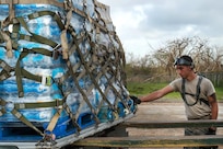 Senior Airman Cody Alverson guides a pallet of water onto a Halvorsen K-loder at Aguadilla.